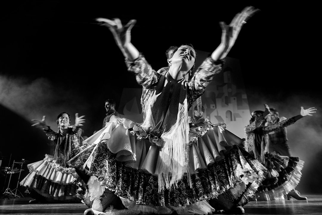 Una bailarina abre los brazos y despliega su vestido.